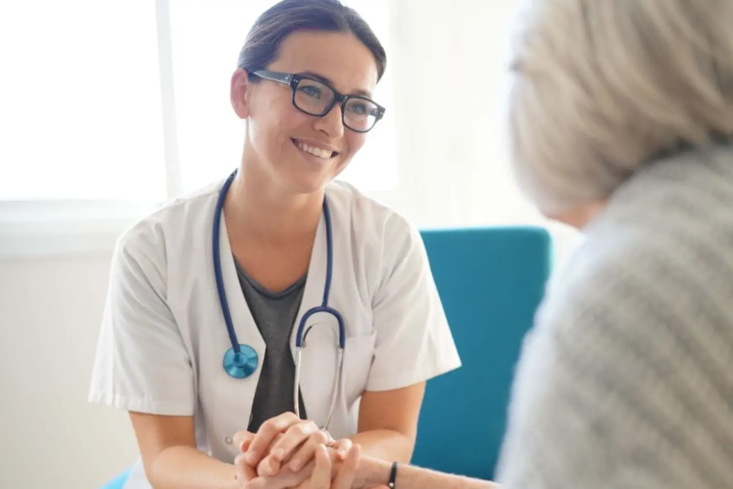 Médica sonriente de la mano de un paciente anciano, servicios nativos de AWS para mejorar la seguridad