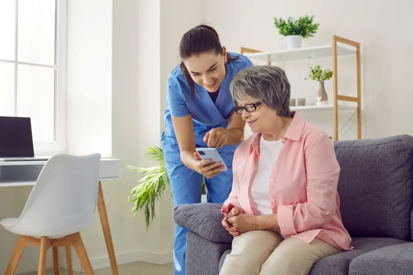 Eine Krankenschwester zeigt einer älteren Frau, wie man eine mobile Gesundheits-App nutzt