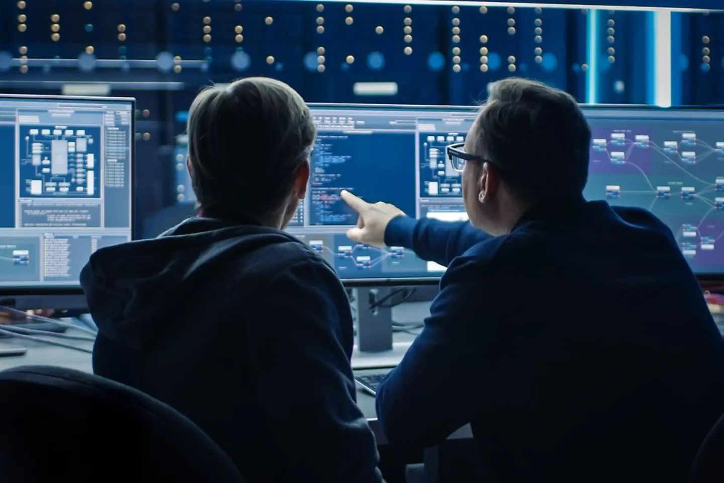 Dois especialistas em software observam uma análise de dados em uma tela de computador