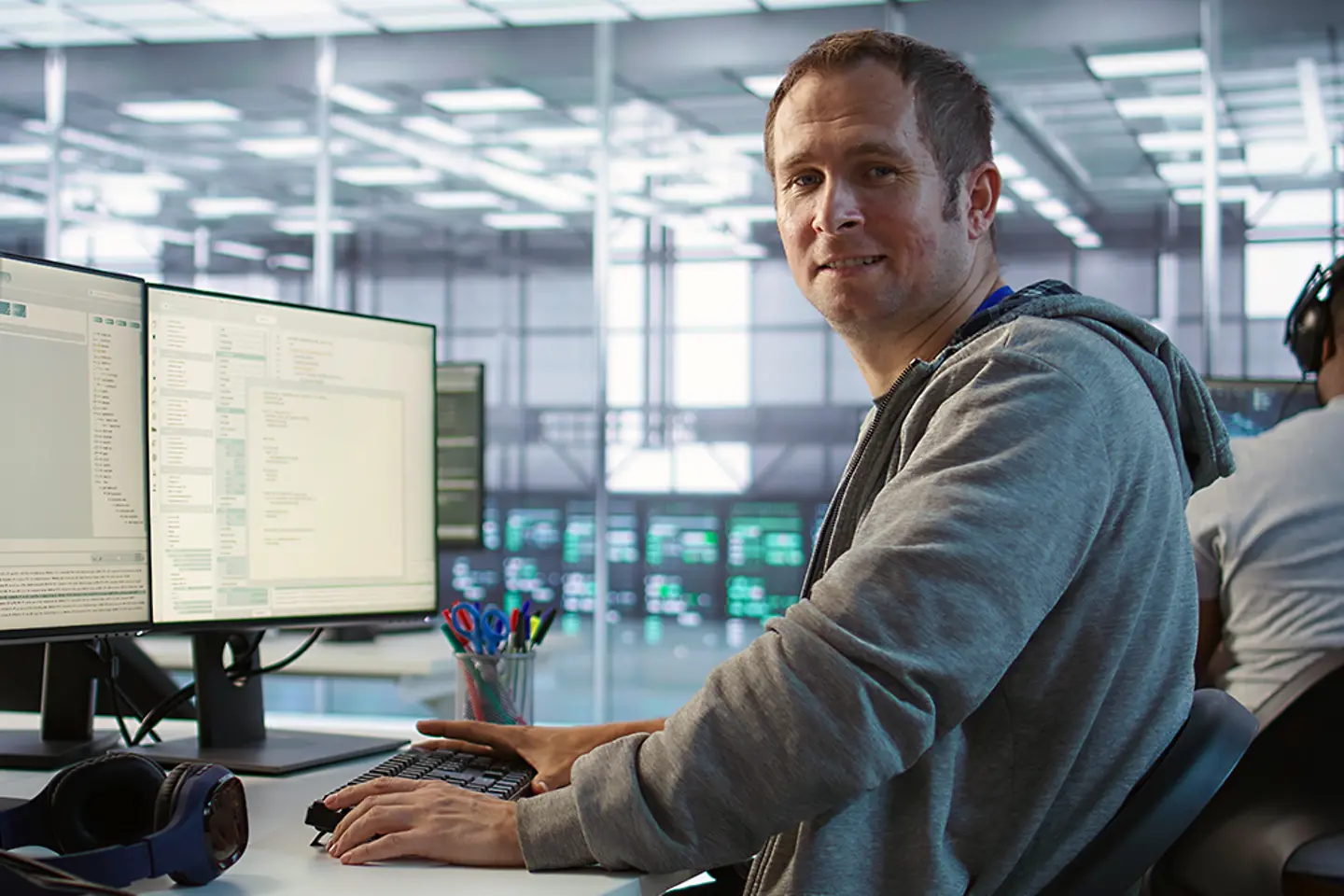 Een glimlachende technicus inspecteert de rijen servers in het datacenter