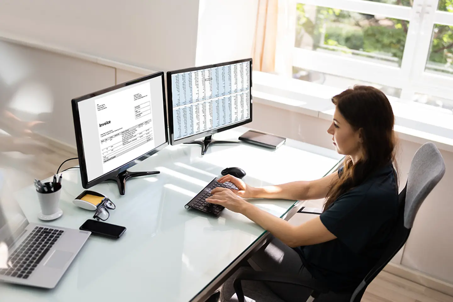 Een accountant gebruikt elektronische factureringssoftware op een desktopcomputer