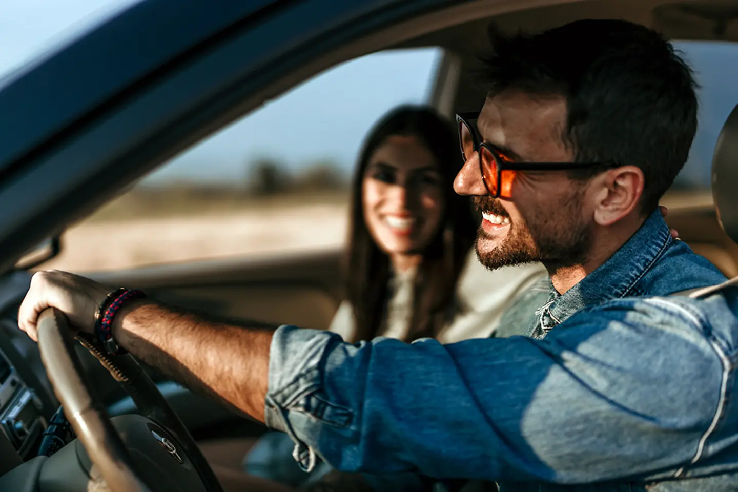 Casal feliz dirigindo juntos em um carro, apreciando um pôr do sol panorâmico em uma viagem de carro 