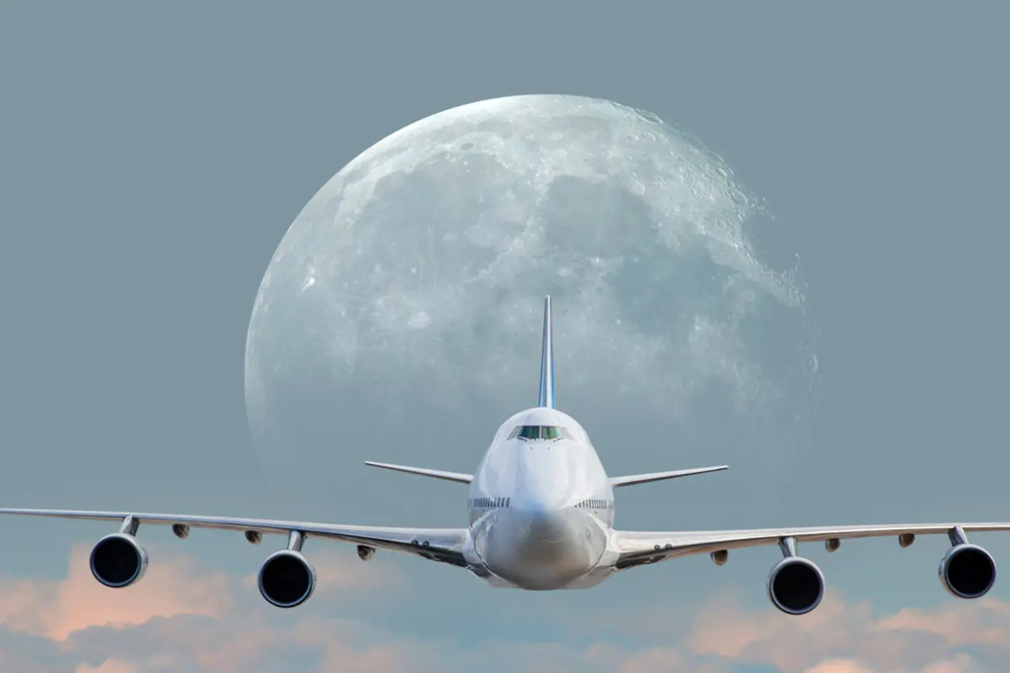 Een wit passagiersvliegtuig boven de wolken bij volle maan
